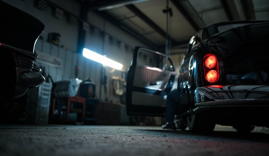 Dimly lit hidden garage revealing silhouettes of covered classic cars