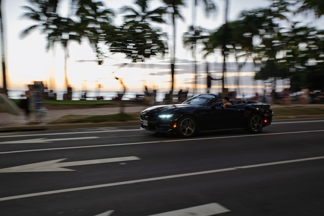 Classic convertible driving along a coastal road near Colonia at sunset